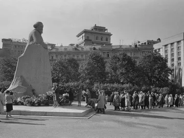 Karl Marx monument with flowers at its base, surrounded by a crowd of people in a black-and-white photograph.