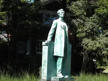 Lincoln the Lawyer bronze statue of Abraham Lincoln on a pedestal in a grassy park setting with a plaque in the foreground.