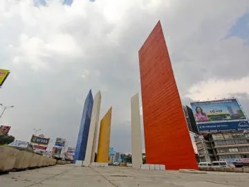 Torres de Satélite with five brightly colored geometric pillars rising against a cloudy sky.