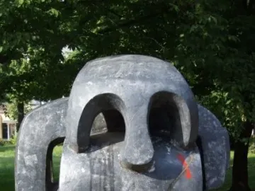 Treblinka memorial abstract dark gray sculpture with carved openings and a red mark on the side