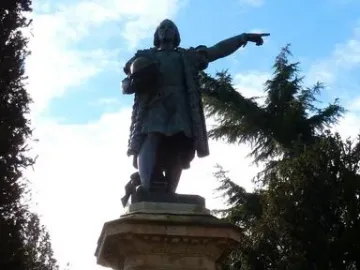 Monument to Columbus: a bronze-toned statue of a man holding a globe and pointing outward on a tall stone pedestal.