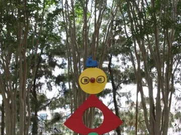 The Caress of a Bird sculpture with stacked brightly colored shapes in a garden setting.