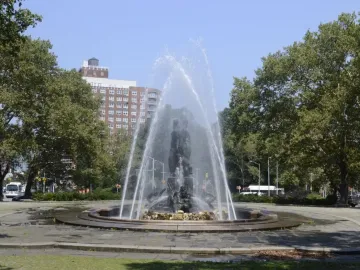 Bailey Fountain with water arcing around dark metallic statues in a circular stone basin.