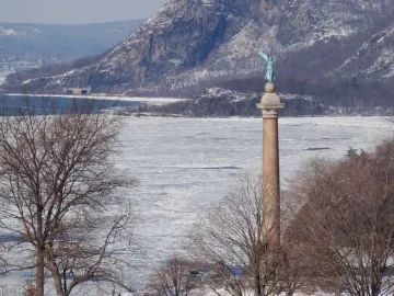 Battle Monument at West Point rising above a frozen river with snowy mountains in the background