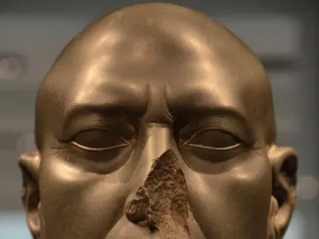 Berlin Green Head, a dark greenish-grey stone head with a damaged nose and broken neck.