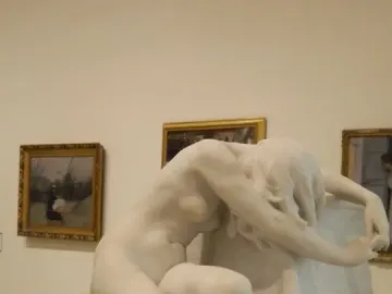 Desolation, a white marble nude female sculpture crouching with her head bowed beside a rough stone base.