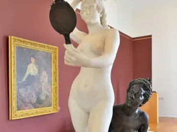 Le Miroir sculpture showing a white marble nude woman holding a hand mirror above a kneeling bronze figure on a decorative base.