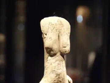 Venus of Eliseevichi figurine with prominent breasts and hips on a white pedestal