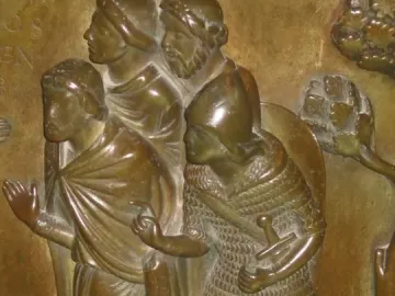 Bronze relief panel from the Baptismal Font at St Bartholomew\'s Church showing four male figures, including one in chainmail with a sword.