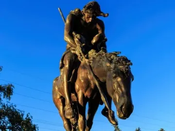 End of the Trail bronze sculpture showing a slumped rider on a lowered horse atop a stone base.