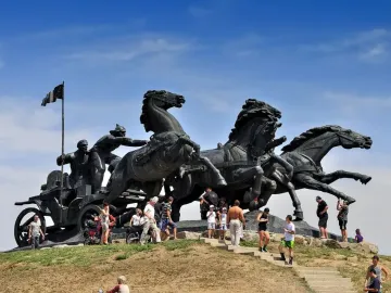 Legendary Tachanka bronze monument with four horses pulling a cart and figures, including one holding a flag.