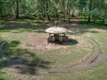 UFO Memorial concrete sculpture with a stylized flying saucer form and circular ring in a grassy clearing