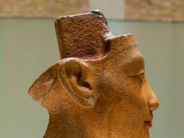Unfinished head and neck sculpture of Nefertiti in profile facing right.