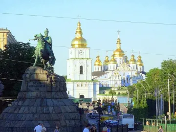 Monument to Bohdan Khmelnytsky on horseback with a cathedral and golden domes in the background.