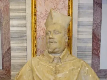 Marble bust of Cardinal Scipione Borghese wearing a clerical hat and buttoned cape, displayed on an ornate pedestal.