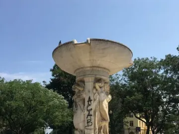 Dupont Circle Fountain with graffiti on one of the sculpted figures and a pigeon perched on top.