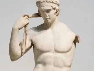 Farnese Diadumenos, a white marble nude male statue adjusting a headband with his right hand and missing his left arm.