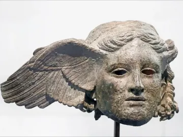 Bronze head of Hypnos with a green patina, serene face, and a wing extending from one side.