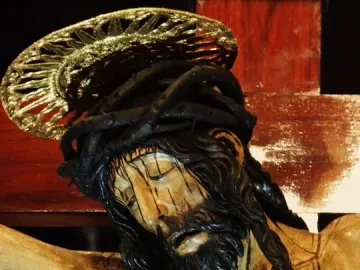 Close-up of Cristo de La Laguna showing the bowed head, closed eyes, crown of thorns, and gilded halo of the wooden crucifix.