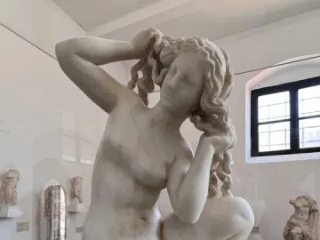 Crouching Venus marble sculpture of a crouching nude woman adjusting her hair in a museum