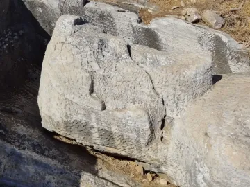 The Kouros of Apollonas, a rough-hewn stone head and upper torso carved from the rock in a quarry setting.