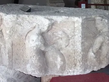 Relief carving on the Pilier d\'Yzeures-sur-Creuse showing two figures on a weathered stone block, with the right figure holding a bow or staff.