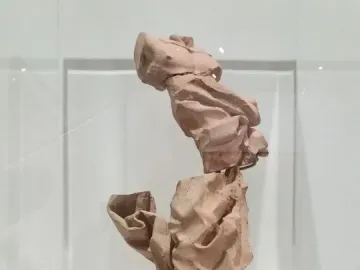 Terracotta model for Bernini’s Saint Longin, shown in stacked, crumpled forms inside a display case on a white pedestal.