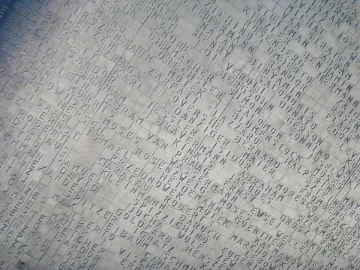 Hailfingen-Tailfingen Memorial name wall covered with hundreds of engraved names in a diagonal grid.