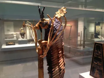 Ram in a Thicket sculpture showing a golden ram standing on hind legs with dark horns and a stylized golden thicket.