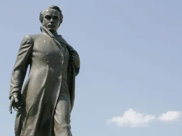 Taras Shevchenko Memorial bronze statue of a man in a long coat against a blue sky