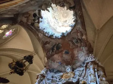The Transparente in Toledo Cathedral, showing a richly carved Baroque altarpiece beneath a circular ceiling opening with painted celestial scenes.