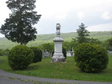 Confederate Memorial stone monument topped with a draped figure holding an urn in a cemetery.