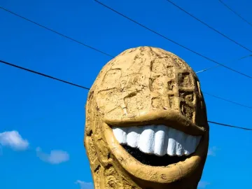 The Jimmy Carter Peanut Statue with a wide grinning mouth and white teeth against a blue sky.