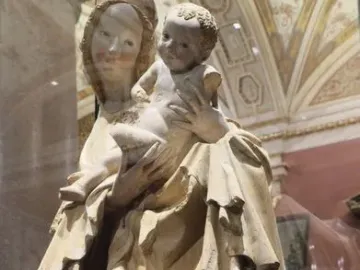 Krumlov Madonna sculpture of a woman holding a child, with flowing carved robes and traces of color on their faces.