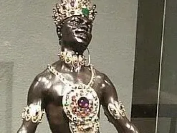 Moor with Emerald Plate statue holding a tray with green crystals, wearing a jeweled crown and ornate gold jewelry.
