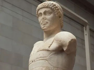 Motya Charioteer marble sculpture showing a worn head, draped torso, and missing arms.
