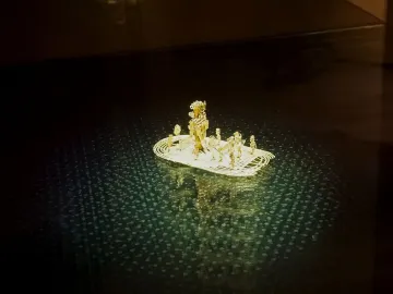 Muisca Raft golden miniature with small figures on a reflective dark surface