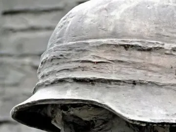 Close-up of the Warsaw Uprising Monument showing a weathered bronze soldier’s profile in a helmet.
