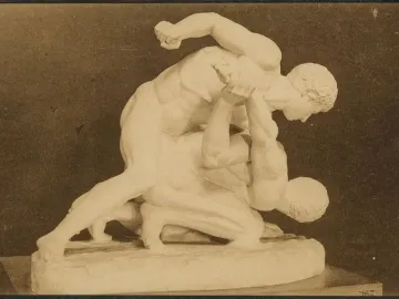 A sculpture of two nude male wrestlers locked in an athletic struggle, one pinning the other down.