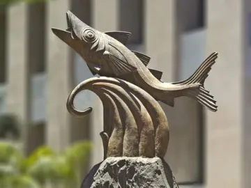 The Chicharro Sculpture showing a metallic fish leaping from a rugged rock pedestal.