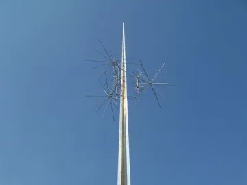 Ad Astra sculpture with a tall reflective spire and spiky star-like forms against a blue sky.