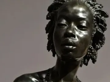 The Nubian Woman bronze bust with an elaborate coiled hairstyle and layered necklace.