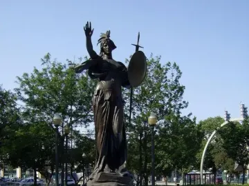Russell Alger Memorial Fountain with a bronze female statue holding a shield and sword in a blue basin.