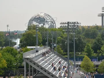 The Unisphere rises above trees and stadium stands under a hazy sky.