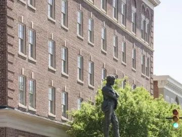 Appomattox bronze statue on a stone pedestal decorated with a red and white wreath at a street intersection.