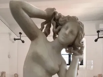 Crouching Venus, a white marble statue of a nude woman crouching with her hands raised to her hair.