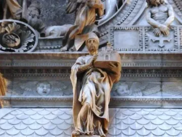 Marble statue of Saint Petronius holding a model of a building within an ornate monument with relief figures and decorative details.