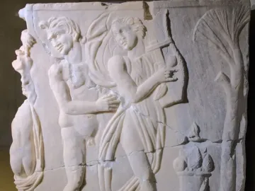 Roman marble relief from the Sarcophagus of the Triumph of Bacchus showing a draped figure playing a lyre beside a nude satyr-like male figure and a small altar or pedestal with fruit.