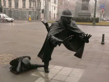 Vaartkapoen bronze sculpture showing a man emerging from a manhole and grabbing a startled policeman\'s ankle.