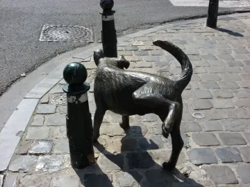 Het Zinneke dog sculpture standing on a cobblestone street beside a green bollard.